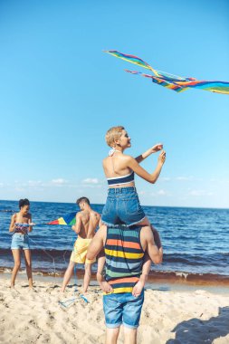 seçici odak Interracial grup arkadaşıyla kumsalda eğleniyor uçurtma ile
