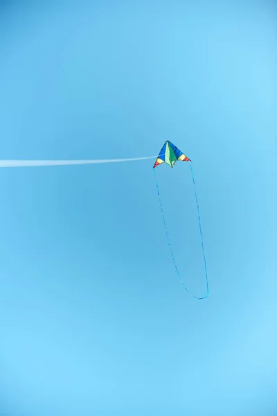 colorful kite flying high in blue clear sky