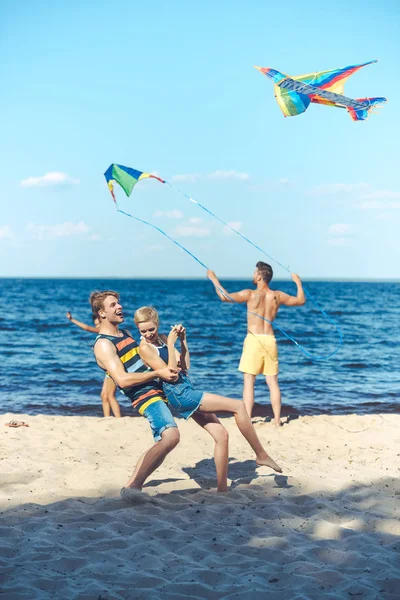 砂浜のビーチで楽しい凧と友達の人種グループの選択と集中  — 無料ストックフォト