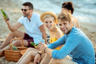 Interracial kumsalda birlikte yaz günü dinlenme bira ile genç arkadaşlar gülümseyen