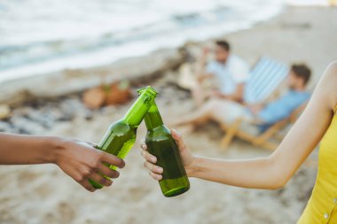 seçici odak çok ırklı arkadaş kumsalda birlikte dinlenme sırasında cam şişe bira tungur