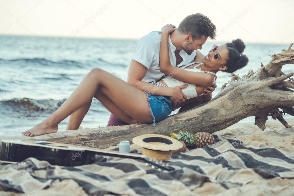 side view of happy multicultural couple resting on beach