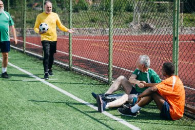 interracial elderly football players after match on green field clipart