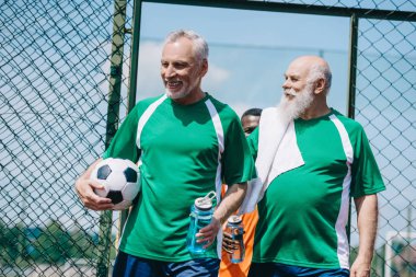 çok kültürlü gülümseyen yaşlı erkeklerle sportif su şişeleri ve futbol topu
