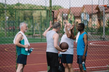 çok ırklı eski sporcular oyun üzerinde birbirlerine beşlik veren basketbol topu ile Grup