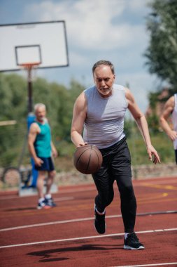 selective focus of old friends playing basketball on summer day clipart