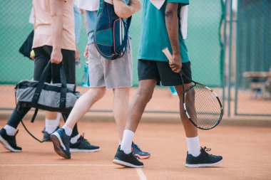 çok kültürlü yaşlı erkekler tenis malzemeleri sahada yürüyüş ile kısmi görünümünü