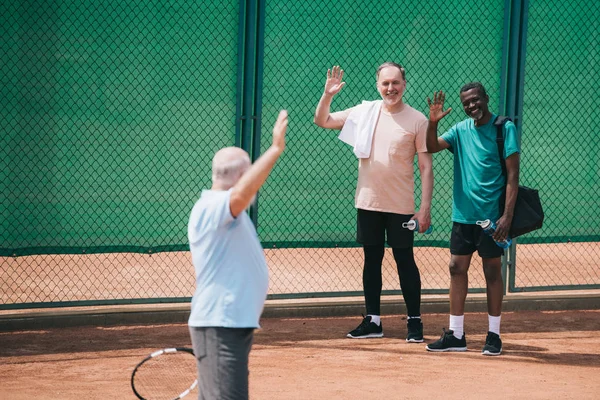 Viejo Multiétnico Saludo Amigo Con Raqueta Tenis Cancha — Foto de stock gratis