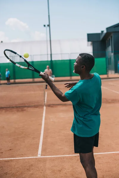selective focus of elderly african american man playing tennis with friend on court