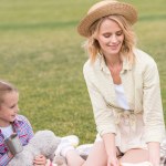 Feliz madre e hija pequeña comiendo sándwiches en el picnic en el parque