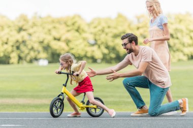 mutlu anne şirin küçük kızı binicilik bisiklet park bakarak yan görünüm