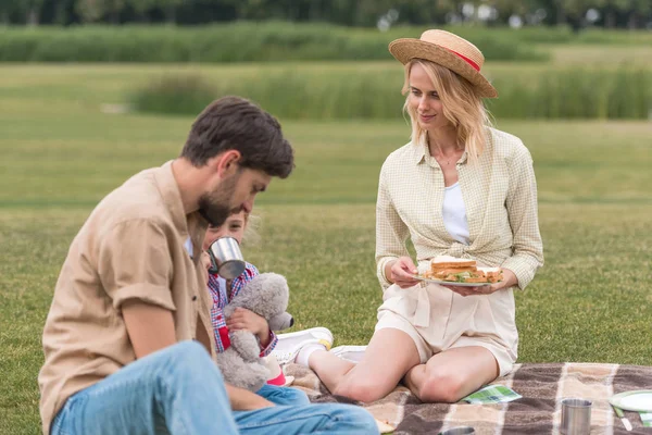ピクニックで格子縞に座ってサンドイッチを食べて つの子供と幸せな家庭 — ストック写真