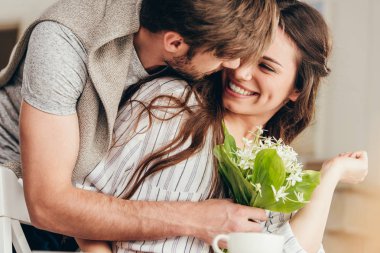 close-up shot of young man presenting flowers bouquet to girlfriend clipart