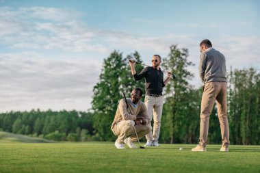 Grup Genç şık çok kültürlü arkadaşıyla birlikte golf oynarken vakit