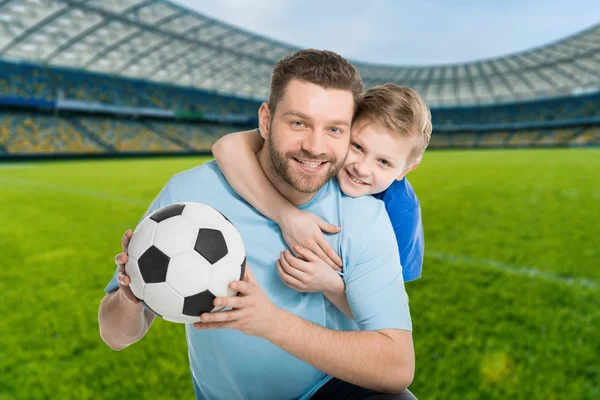 happy father an son with football ball on stadium
