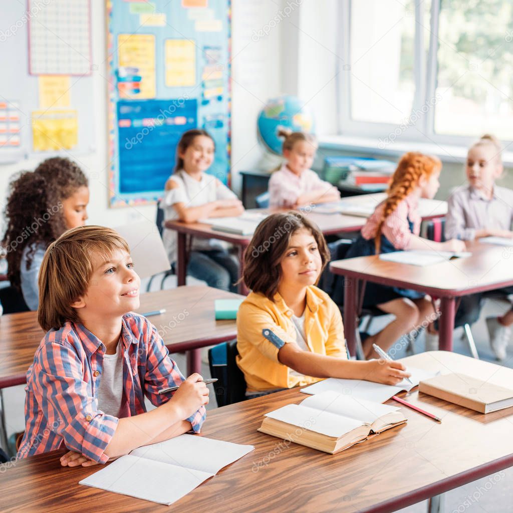 concentrated little kids listening teacher in class on lecture