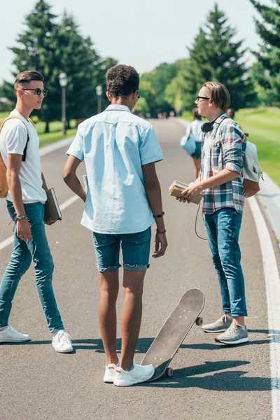 Multietniskt Tonårspojkar Med Böcker Och Skateboard Står Och Pratar Park — Stockfoto