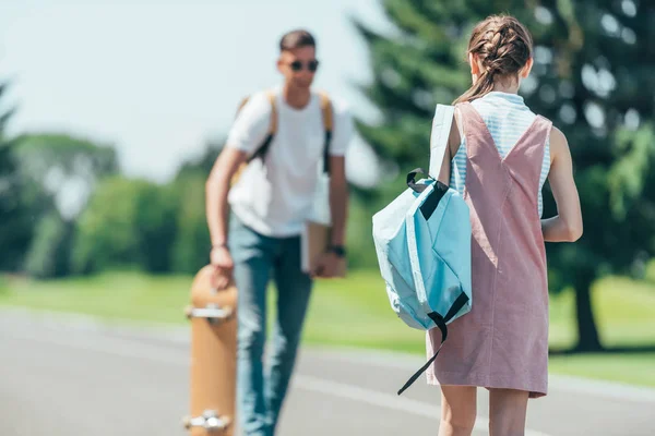 Vista Trasera Adolescente Con Mochila Mirando Amigo Con Monopatín Parque — Foto de Stock