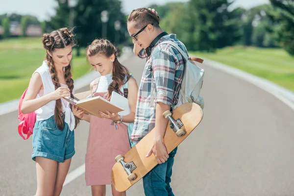 Estudantes Adolescentes Com Mochilas Skate Ler Livro Juntos Parque — Fotografia de Stock