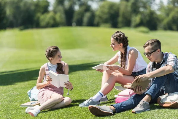 Uśmiechający Się Nastoletnimi Studentami Książek Cyfrowego Tabletu Siedząc Trawie Nauka — Zdjęcie stockowe