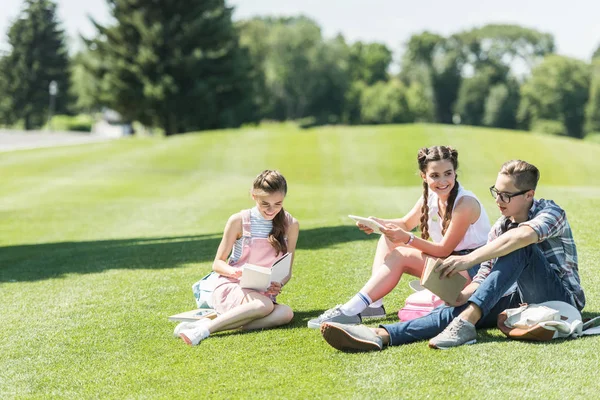 Smiling Teenage Students Sitting Grass Studying Books Digital Tablet Park — Stock Photo, Image