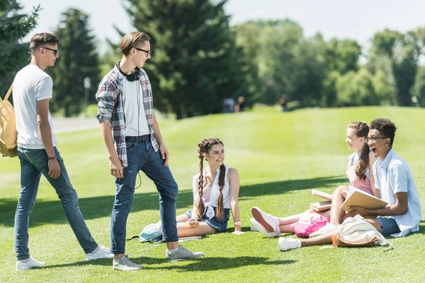 代の同級生が公園で勉強を見て笑みを浮かべて男の子 — ストック写真