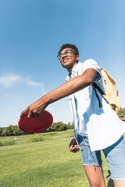 Lächelnder Afrikanisch Amerikanischer Teenager Mit Rucksack Wirft Fliegende Scheibe Park — Stockfoto