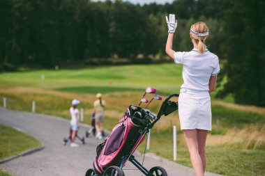 seçici odak kadın golf oyuncusu kap ve arkadaşları tebrik golf sahasında golf dişli ile beyaz polo