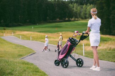seçici odak kadın golf oyuncusu kap ve beyaz polo ile golf golf sahasında dişli