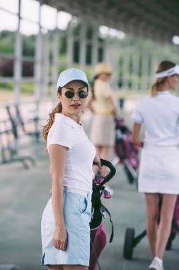 seçici odak kadın güneş gözlüğü ile golf sahası kameraya bakarak golf dişli