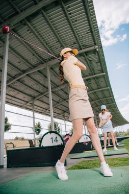 low angle view of women with golf clubs playing golf at golf course clipart