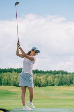 polo, güneş gözlüğü ve golf sahasında golf oynarken kap kadın yan görünüm