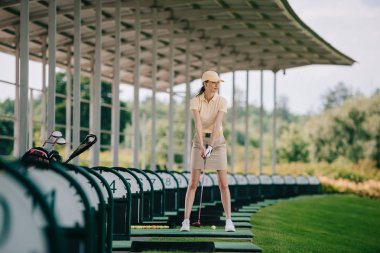 Kadın sarı kap ve golf sahasında golf oynarken polo