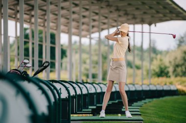 Kadın sarı kap ve golf sahasında golf oynarken polo