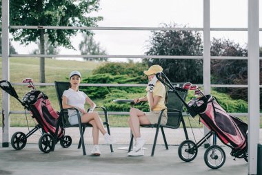 kadın Smartphone cep telefonu ile arkadaş yakınındaki tarafından golf oyunu sonra dinlenme süre söz