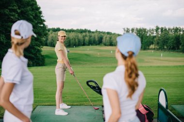 kadın golf oyuncu arkadaş golf sahasında bakarak gülen seçici odak