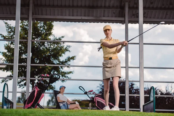 Selective Focus Female Golf Player Playing Golf While Friend Resting — Free Stock Photo