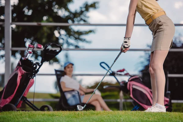 友人の背後にあるゴルフ場で休憩しながらゴルフ女子ゴルフ選手の部分的なビュー  — 無料ストックフォト