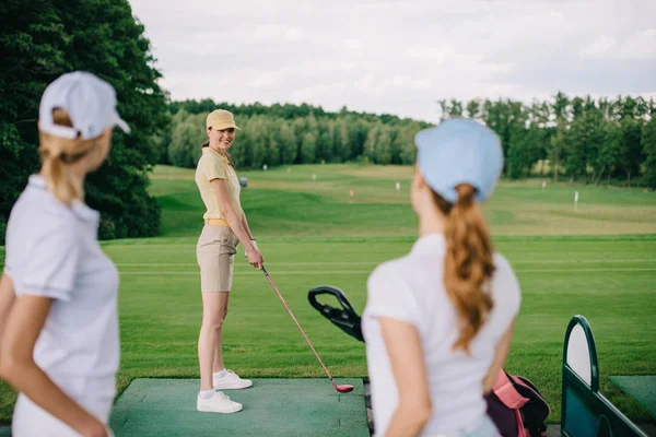 ゴルフ場で友人を見て女性ゴルフ選手の笑顔の選択と集中 — ストック写真