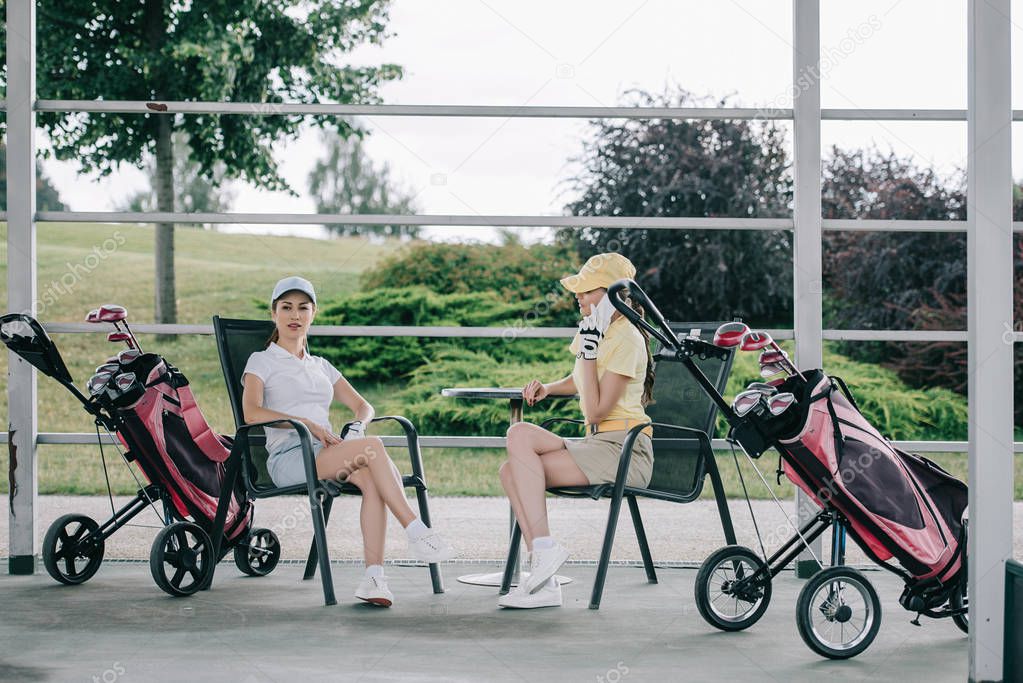 Woman talking on smartphone while friend resting near by after golf game