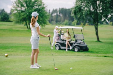 seçici odak olan golf club golf arabası yeşil çimenlerin üzerine oturan arkadaşlar bakarak kadın