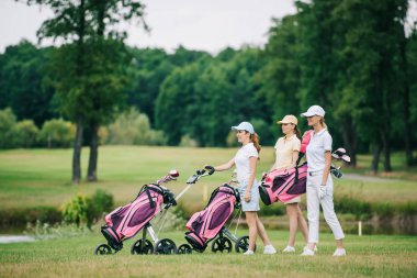 kadın golf oyuncuları kapaklar golf sahasında golf ekipmanları ile yan görünüm