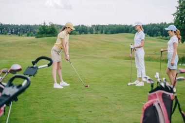 oynarken golf golf sahasında yakınındaki beklemede arkadaş süre şapkalı kadın yan görünüm