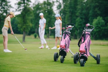 golf vites seçici odak, golf ve golf sahasında yakınındaki beklemede arkadaşlar oynarken şapkalı kadın