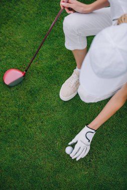 yeşil çim golf sahasında topu koyarak kap ve golf eldiven içinde kadın havai görünümü