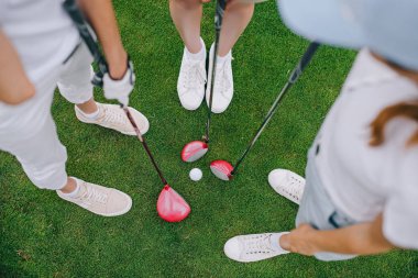 kadın golf oyuncuları ile golf kulüpleri golf topu orta ile yeşil çim üzerinde duran havai görünümü