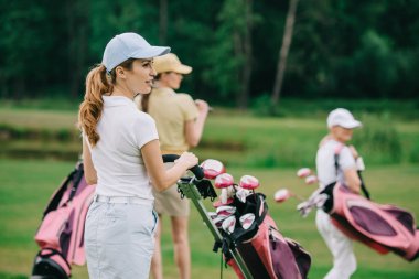 seçici odak kapaklar golf vites golf sahasında yeşil çim üzerinde yürüme ile kadınların