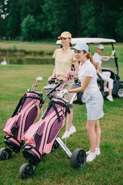 kadın golf oyuncu golf ekipmanları ve golf arabasında yeşil çim arkadaşıyla seçici odak
