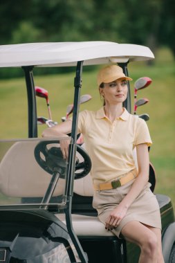 polo ve golf arabasında oturuyor ve uzağa arıyorsunuz kap içinde gülümseyen kadın portresi