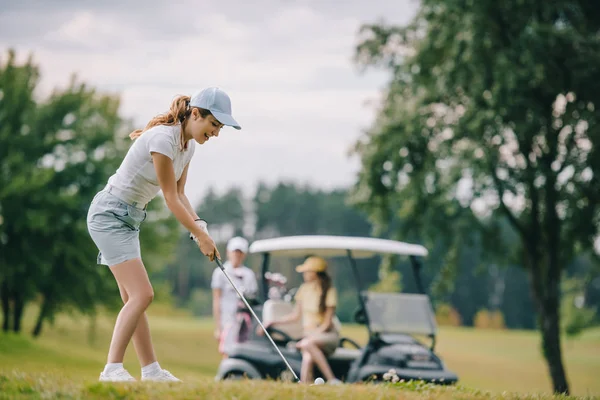 高尔夫球俱乐部妇女的选择焦点高尔夫球场和朋友在绿色草坪上的高尔夫球车休息 — 图库照片
